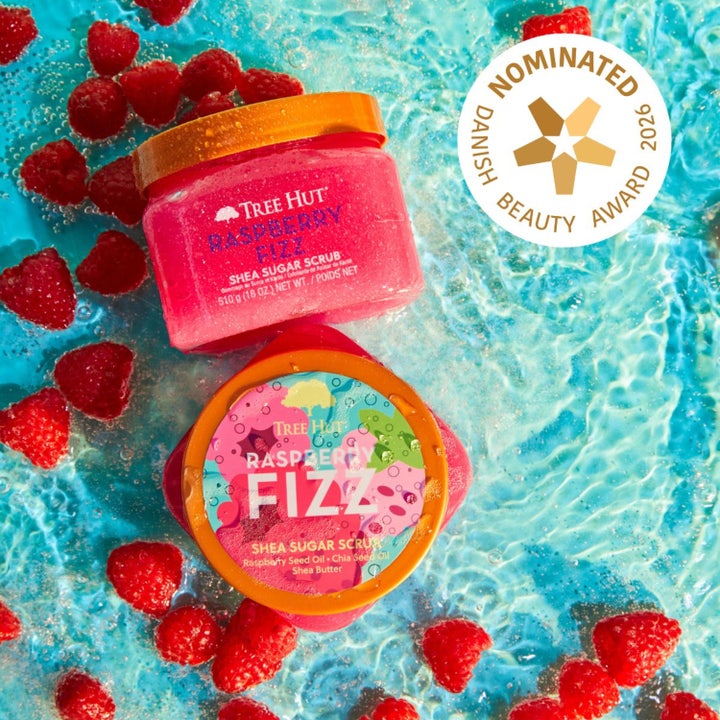 Tree Hut Shea Sugar Scrub Raspberry Fizz 510 g body scrub i pink krukke omgivet af friske hindbær i blåt vand