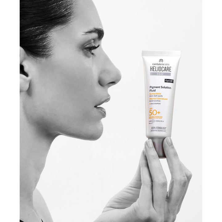 Heliocare Pigment Solution Fluid SPF 50+ 50 ml solcreme mod mørke pletter i hvid tube holdt af en kvinde