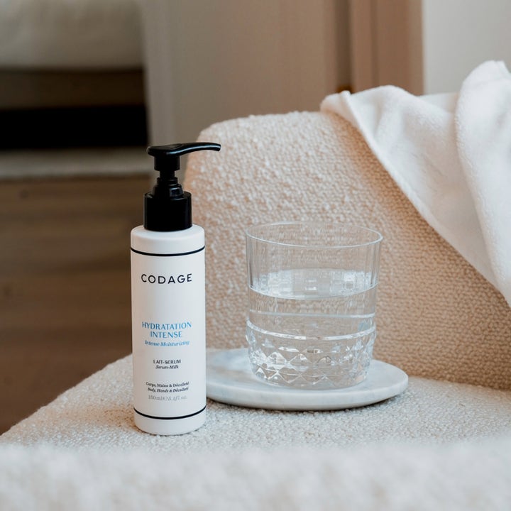 Codage Paris The Body Serum-Milk 150 ml giver intens fugt i hvid pumpeflaske placeret ved et glas vand