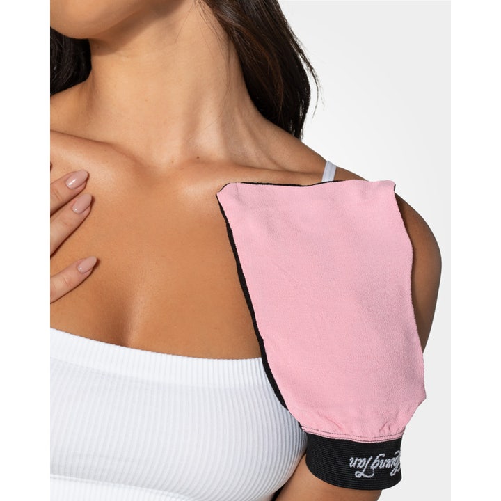 Loving Tan Tan Removing & Skin Polishing Glove 1 stk eksfolierer huden lyserød og sort handske vist på en skulder