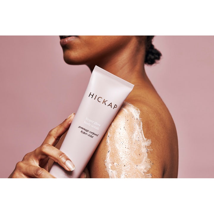 Hickap Hyper Glow Body Scrub Beige 150 ml eksfolierende scrub i beige tube påført på skulder med synlig tekstur.