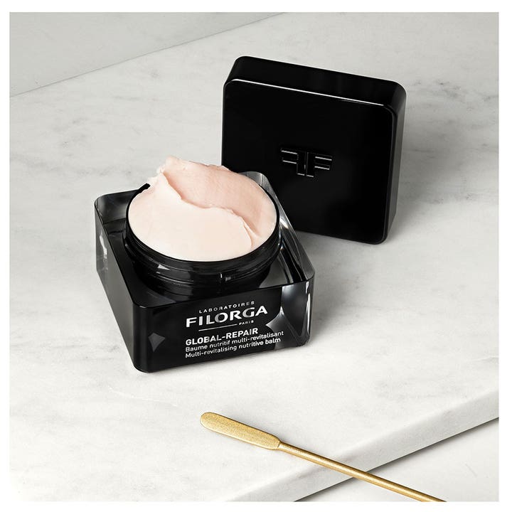 Filorga Global-Repair Balm 50 ml nærende dagcreme i sort krukke med cremet lyserød konsistens og guldspatel.