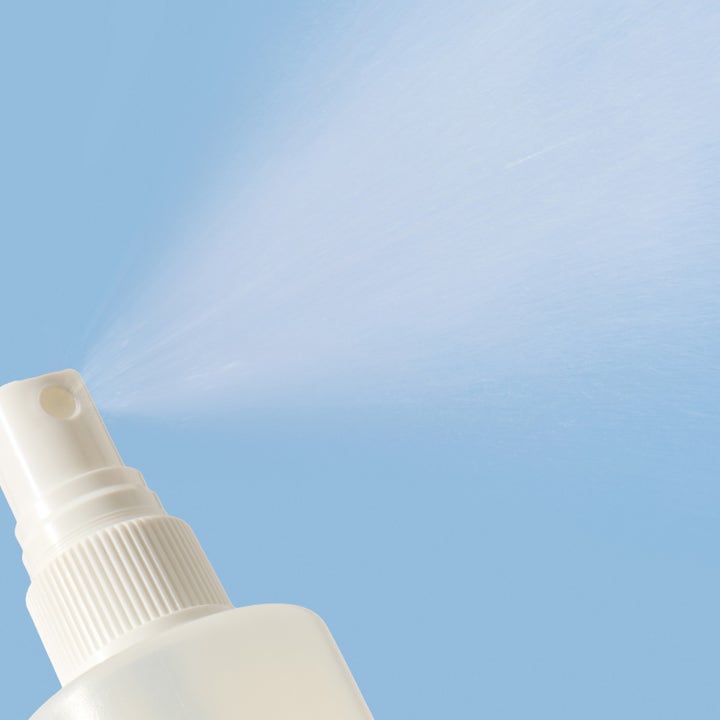 Mario Badescu Back And Body Clarifying Spray 236 ml mod urenheder viser en fin tåge fra hvid spraydyse mod blå baggrund.