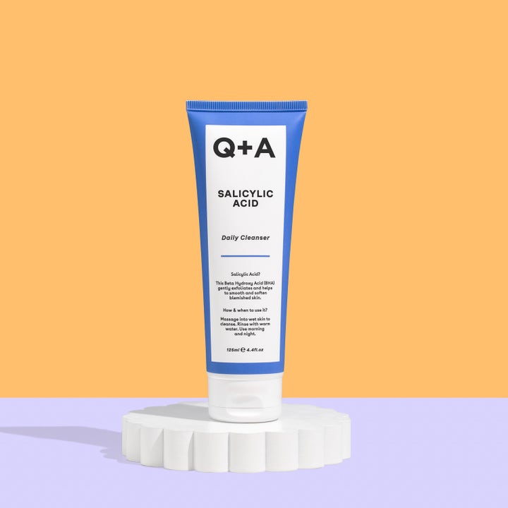 Q+A Salicylic Acid Cleanser 125 ml eksfolierende ansigtsvask i blå tube på en hvid piedestal