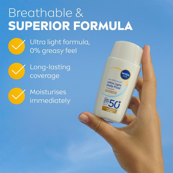 NIVEA UV Face Ultra Fluid 40 ml solcreme til ansigtet spf 50 med hyaluron og medium farve holdt mod blå himmel.