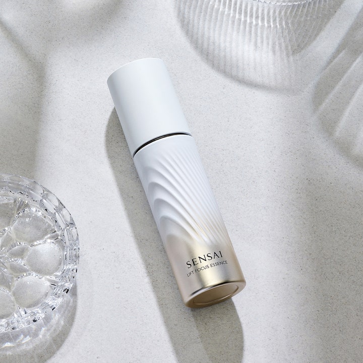 Sensai Lift Focus Essence 40 ml opstrammende serum i hvid og guld flaske med bølgemønster på stenoverflade