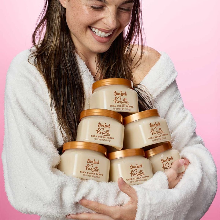 Tree Hut Shea Sugar Scrub Vanilla 510 g eksfolierende body scrub holdt af en smilende kvinde i en hvid badekåbe