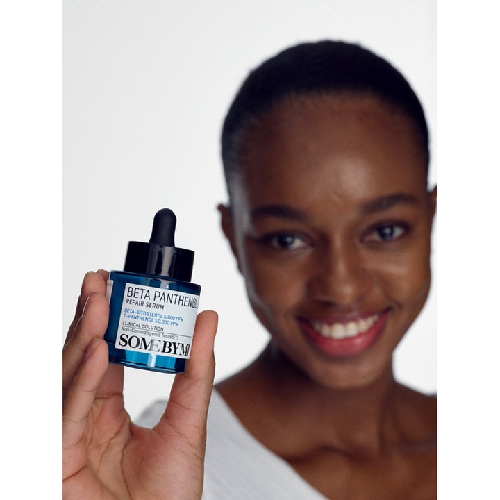 Some By Mi Beta Panthenol Repair Serum 30 ml styrkende serum i blå glasflaske holdt af en smilende kvinde.