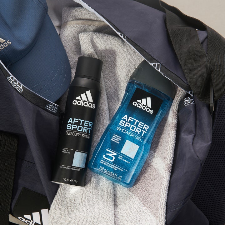 Adidas After Sport 250 ml shower gel og deospray i en blå sportstaske med et gråt håndklæde og kasket.