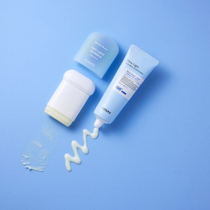 COSRX Airy-Light Invisible Sun Stick 19 g SPF 50 solbeskyttelse vist som stick og tube med hvid creme på blå baggrund