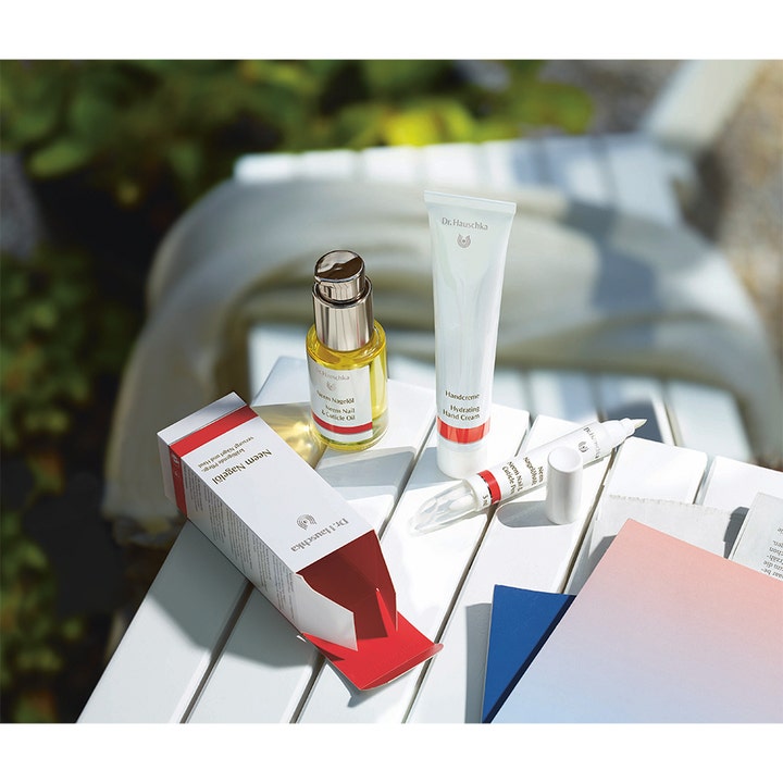 Dr. Hauschka Hand Cream 50 ml plejende håndcreme i hvid tube ved siden af negleolie i solrigt udemiljø.