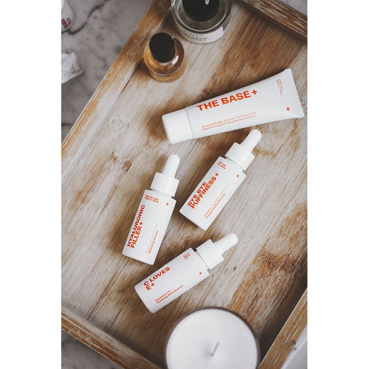 Swiss Clinic C LOVES E+ 30 ml serum med C-vitamin giver glød i hvid pipetteflaske på en rustik træbakke.