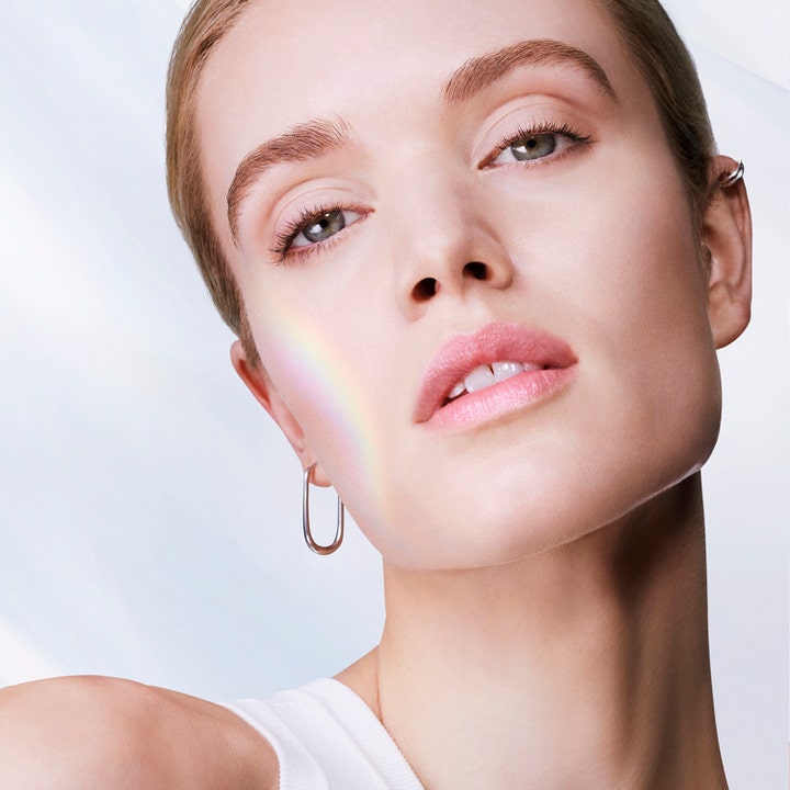 Lancôme UV Expert Supra Screen SPF50 40 ml solcreme giver glød vist på model med en regnbue-lysrefleks
