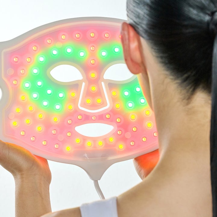 Currentbody Skin LED 4-in-1 Mask ansigtsmaske der viser de lysende røde, grønne og gule LED-lys mod huden