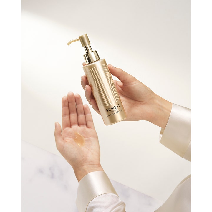 Sensai Ultimate The Cleansing Oil 150 ml luksuriøs renseolie i guldflaske med pumpe og olie i håndfladen