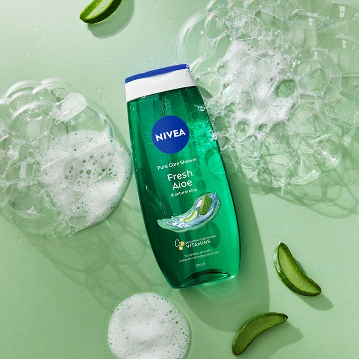 NIVEA Fresh Aloe Shower Gel 250 ml i grøn flaske omgivet af forfriskende skum og friske aloe vera-stykker.