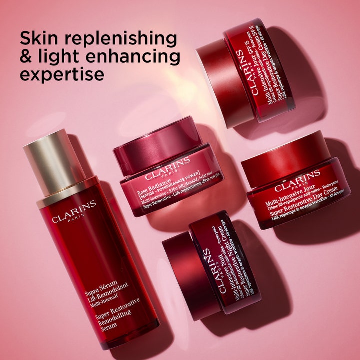 Clarins Rose Radiance 50 ml glødgivende dagcreme i rød glaskrukke omgivet af andre Super Restorative produkter.