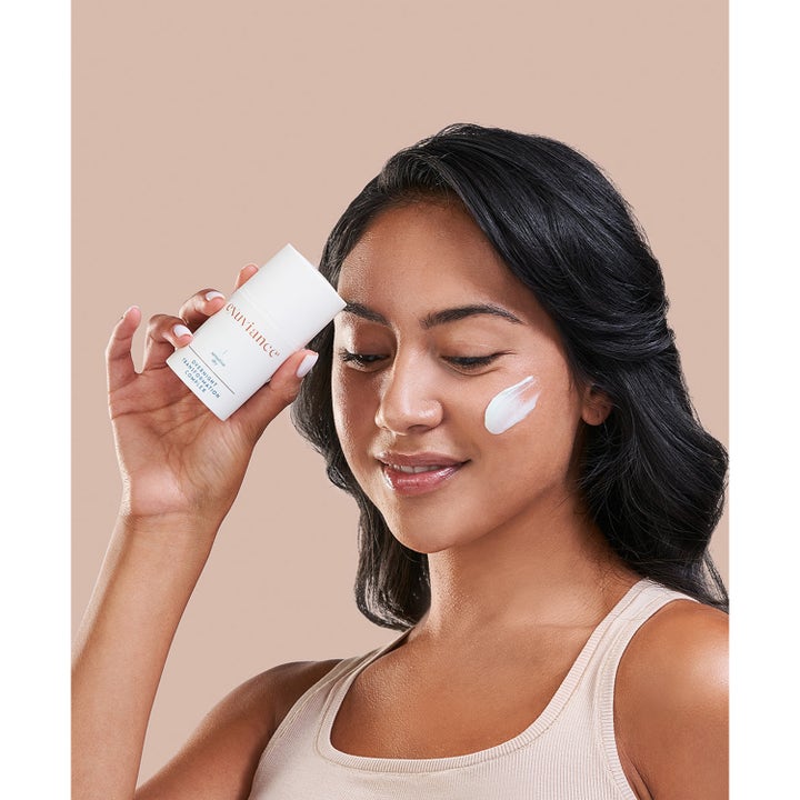 Exuviance Overnight Transformation Complex 50 g fugtgivende natcreme vist på en kvinde med creme på kinden.