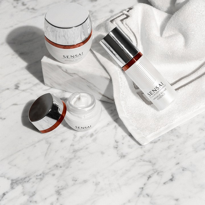 Sensai Cellular Performance Wrinkle Repair Essence 40 ml anti-aging essence i hvid pumpeflaske på et hvidt håndklæde