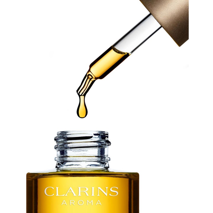 Clarins Santal Face Treatment Oil 30 ml beroligende ansigtsolie med en gylden dråbe fra pipette over glasflaske
