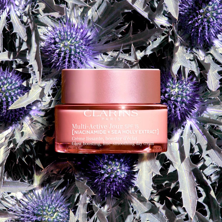 Clarins Multi-Active Jour 50 ml glødgivende dagcreme med niacinamid i lyserød krukke på lilla blomster