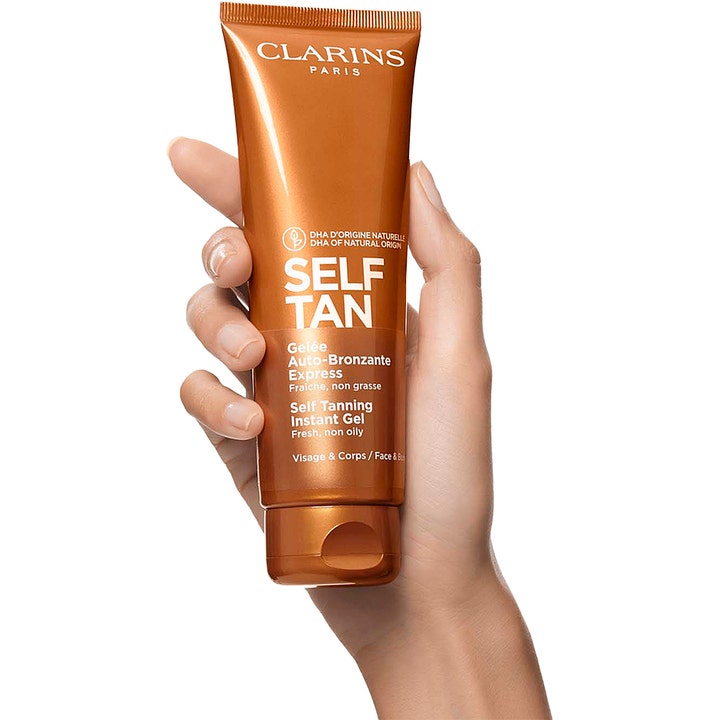 Clarins Self Tanning Instant Gel 125 ml selvbruner i bronze tube der holdes i en hånd