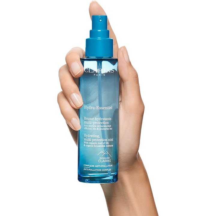 Clarins Hydra-Essentiel 75 ml fugtgivende face mist i blå gennemsigtig flaske holdt af en hånd