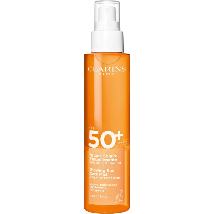 Clarins Glowing Sun Care Mist SPF 50+ solbeskyttende mist der giver glød i en orange sprayflaske med hvid pumpe