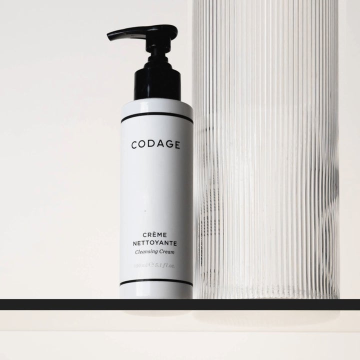 Codage Paris The Cleansing Cream 150 ml fugtgivende ansigtsrens i hvid flaske med sort pumpe ved en glasvase