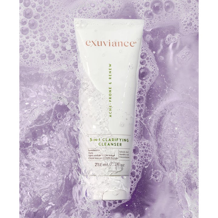 Exuviance 3-in-1 Clarifying Cleanser 212 ml eksfolierende ansigtsrens i hvid tube i lilla vand med bobler