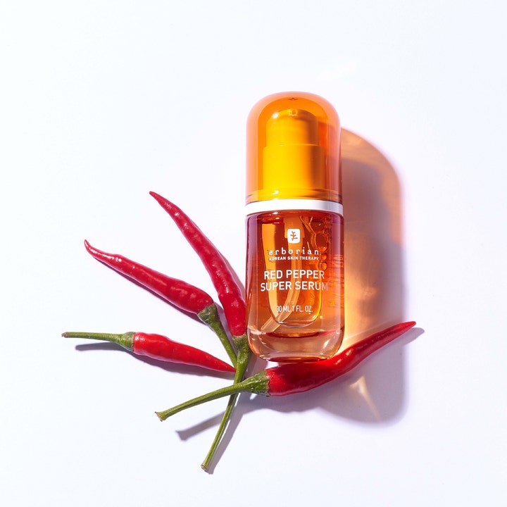 Erborian Red Pepper Super Serum 30 ml energigivende ansigtsserum i orange glasflaske omgivet af friske røde chilier.