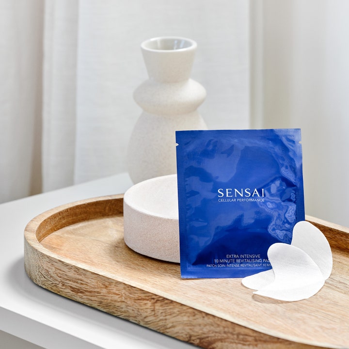 Sensai Cellular Performance Extra Intensive pads 60 g i blå indpakning på en træbakke giver fornyet glød.