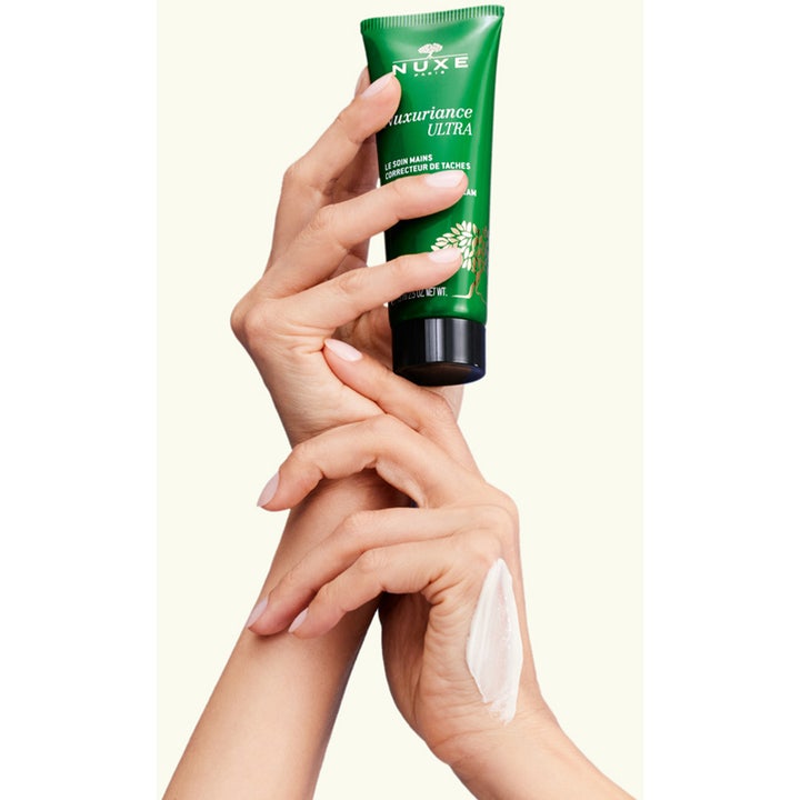 Nuxe Nuxuriance Ultra 90 g handcreme mod pigmentpletter i grøn tube påført hænder med hvid creme
