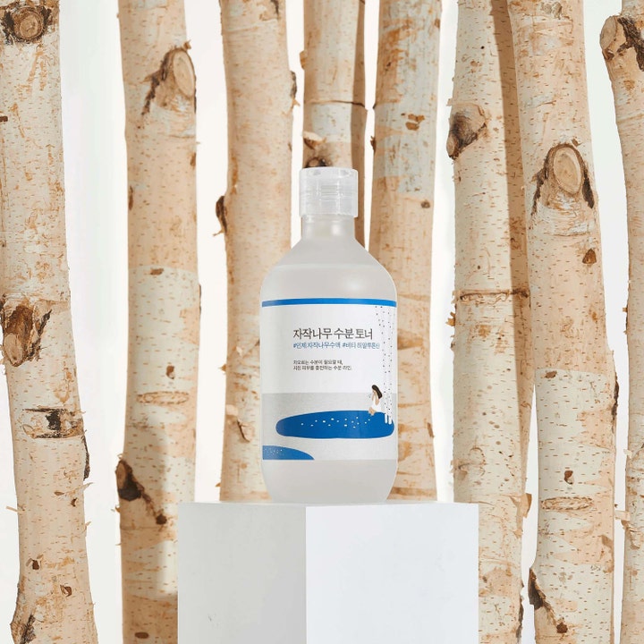 Round Lab Birch Juice Moisturizing Toner 300 ml fugtgivende ansigtstoner i klar flaske placeret mellem birkestammer