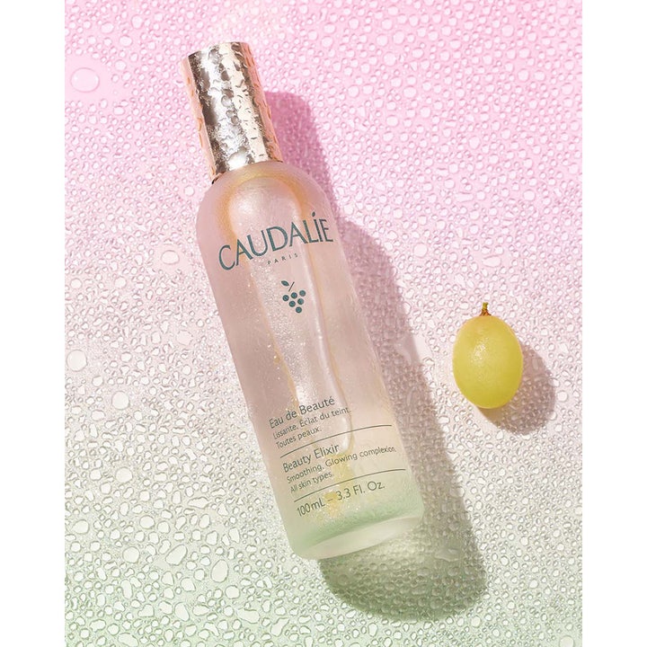 Caudalie Beauty Elixir 100 ml toner der giver glød i frostet glasflaske med guldhætte ved en grøn vindrue