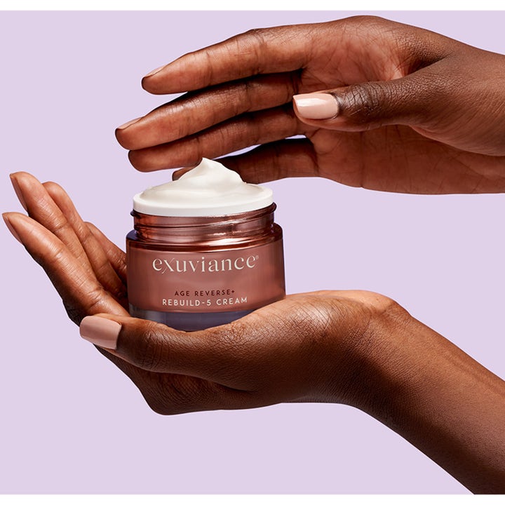 Exuviance Age Reverse + Rebuild-5 Cream 50 ml opstrammende dagcreme i bronze krukke holdt af hænder