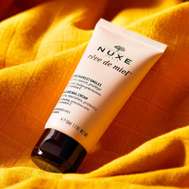 Nuxe Rêve de Miel Hand and Nail Cream 50 ml nærende håndcreme i beige tube på et gult tekstureret stof