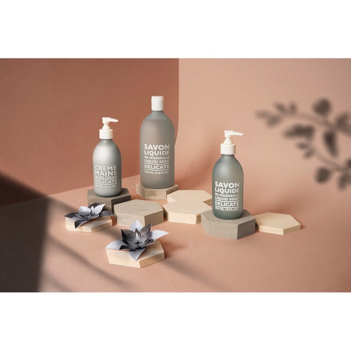 Compagnie de Provence Liquid Marseille Soap Delicate 300 ml flydende sæbe i grå flaske på sekskantede podier.