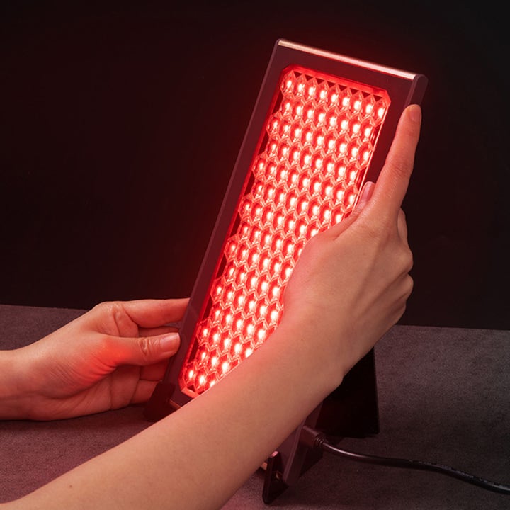 FAQ Swiss FAQ™ Led Panel 1 stk hudplejeværktøj til lysterapi holdt af hænder med et rødt lysende bikubemønster