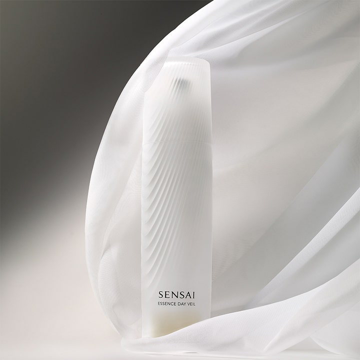 Sensai Essence Day Veil 40 ml dagcreme i hvid riflet flaske omgivet af elegant hvidt svævende stof.