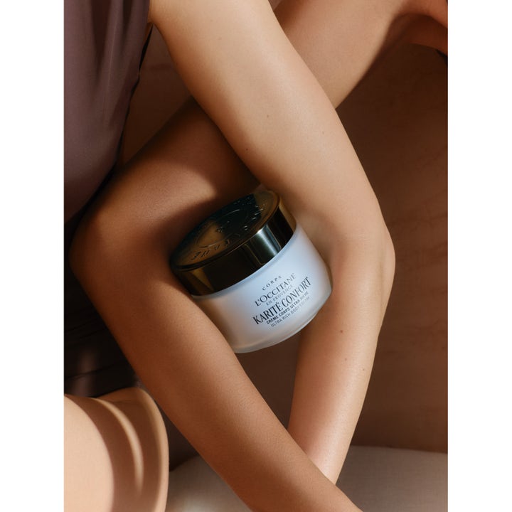 L'Occitane Shea Butter Ultra Rich Body Cream 200 ml fugtgivende creme i krukke med mørkt låg holdt af en person.