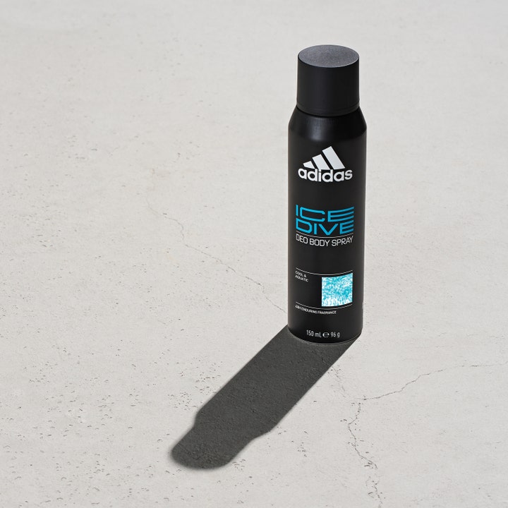Adidas Ice Dive For Him 150 ml frisk deospray i sort flaske med blåt logo stående på en rå betonflade.