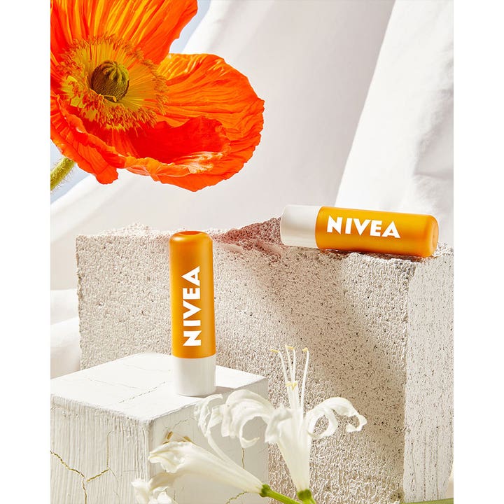 NIVEA Sun Protect Sunstick 4 g solbeskyttelse i orange stifter placeret på sten ved en orange valmue