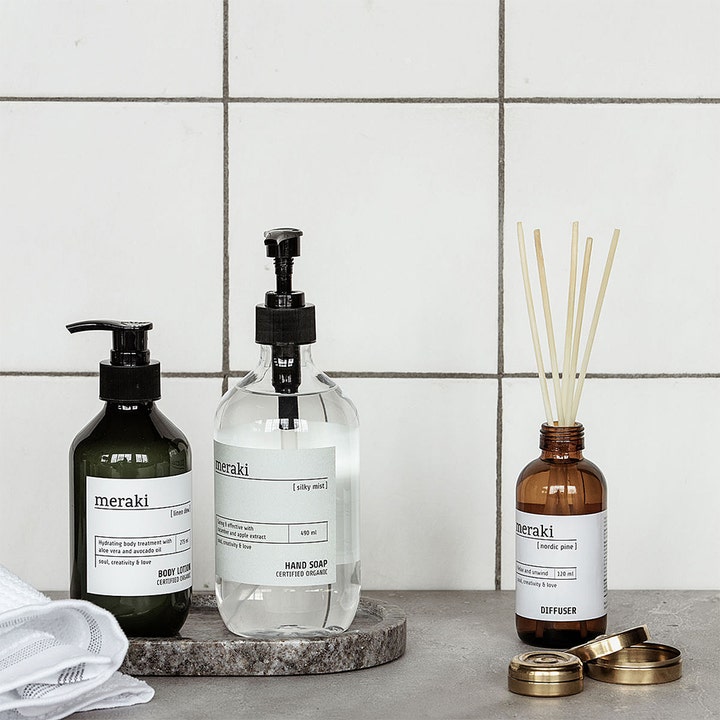 Meraki Linen Dew Body Lotion 275 ml fugtgivende økologisk kropspleje i mørk pumpeflaske i et badeværelsesmiljø