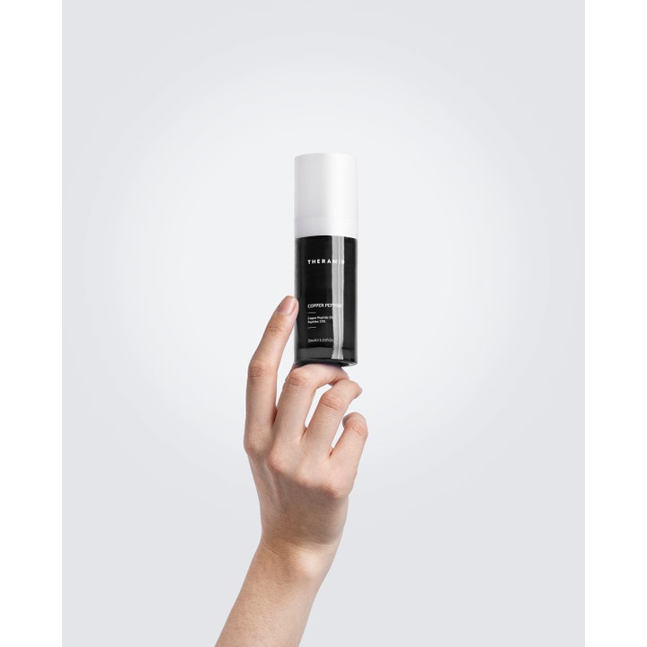 Niche Beauty Lab Theramid Copper Peptide 30 ml anti-aging serum i en sort flaske med hvidt låg holdt af en hånd