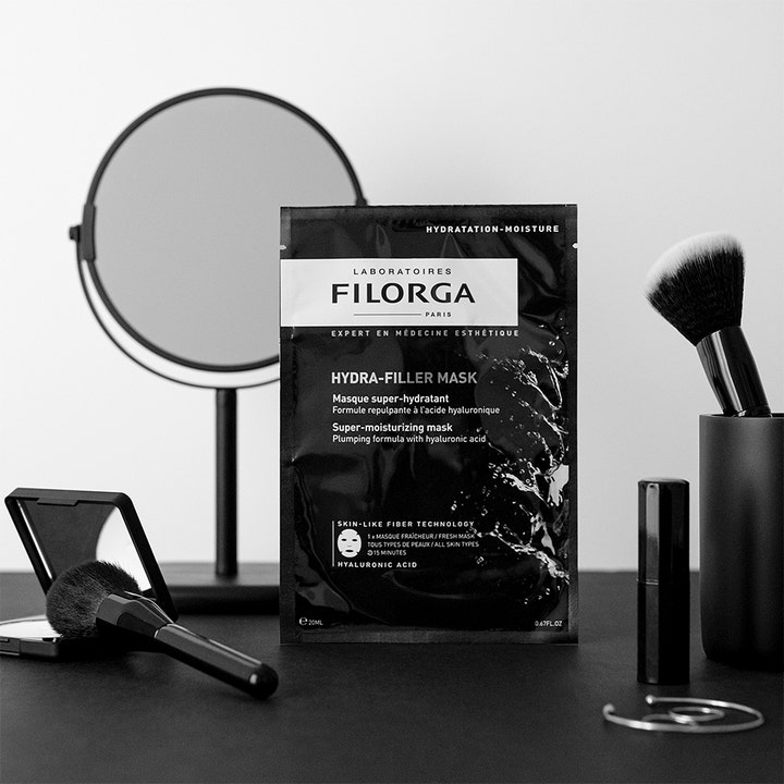 Filorga Hydra-Filler Mask 23 g fugtgivende sheet mask med hyaluronsyre i sort sachet ved siden af et spejl.