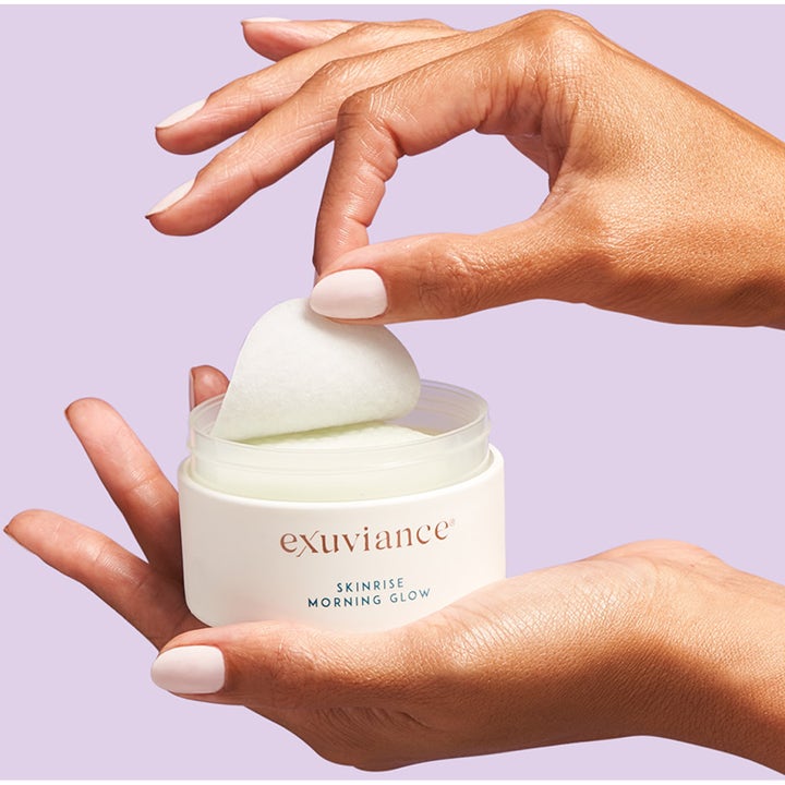 Exuviance SkinRise Morning Glow 36 stk glødgivende serumrondeller i hvid krukke der holdes i hænderne