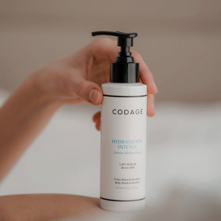 Codage Paris The Body Serum Milk 150 ml fugtgivende bodylotion i hvid flaske med sort pumpe holdt af en hånd