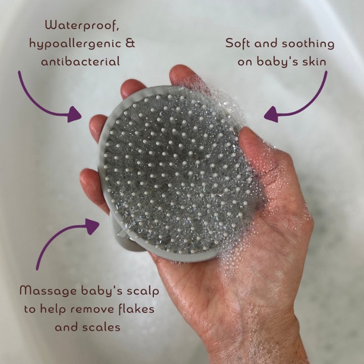 Kokoso Bath Brush 1 stk til babybad er en blød grå silikonebørste i en hånd med skum der fjerner arp og beroliger.