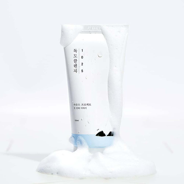 Round Lab 1025 Dokdo Cleanser 150 ml fugtgivende ansigtsrens i hvid tube omgivet af luftigt hvidt skum